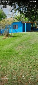 伊塔蒙蒂Casa e camping Reinaldo e Julia recanto das árvores的一座蓝色的建筑,位于一个草地庭院内