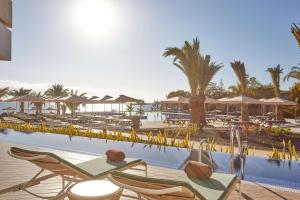 普拉亚布兰卡Dreams Lanzarote Playa Dorada Resort & Spa的一个带椅子和遮阳伞的游泳池的度假酒店