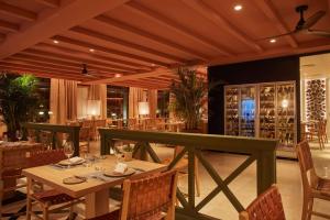科拉雷侯Secrets Bahía Real Resort & Spa Adults only的餐厅设有桌椅和葡萄酒瓶