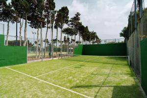 萨尔加Alua Illa de Menorca的一个带绿色围栏和树木的网球场