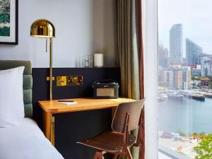 伦敦TRIBE London Canary Wharf的酒店客房设有一张桌子、一张床和一个窗户。