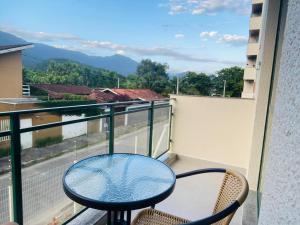 卡拉瓜塔图巴Apartamento beira mar vista para montanha em Massaguaçú的美景阳台配有桌椅