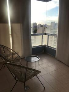 布宜诺斯艾利斯Excelente departamento con ubicación ideal的阳台配有两把椅子和一张桌子,位于窗户前
