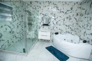 阿克拉Elegant and Cosy Four Bedroom Home in Accra的带浴缸和玻璃淋浴间的浴室。
