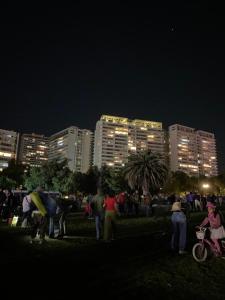 圣地亚哥Kennedy Premium Apartments的一群人晚上站在公园里