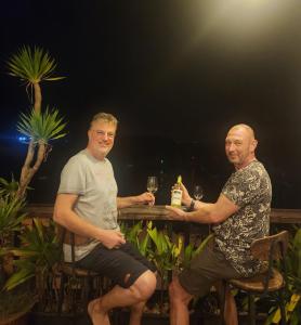 Tân HiệpMonkey Homestay & Bar的坐在桌子旁的两个人,拿着酒杯