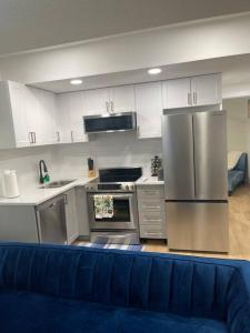 埃德蒙顿Modern 2Bedroom suite in SW Edmonton close to Edmonton International Airport的一间带不锈钢用具和蓝色沙发的厨房