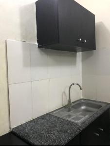 AbeokutaF&B Service Apartment的厨房柜台设有水槽和黑色橱柜。