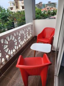蒙巴萨Kezmo Siloam Paradise的阳台上配有两把红色椅子和一张白色桌子