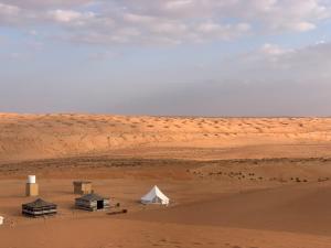 BadīyahThousand Stars Desert Camp的沙漠中的一组帐篷和白色帐篷
