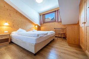 塞尔瓦迪加尔代纳山谷Week End Senoner的木制客房内的一间卧室配有一张大床