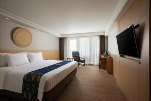 日惹Aveta Hotel Malioboro的配有一张床和一台平面电视的酒店客房
