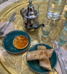 拉巴特DAR LALLA Aicha 2的一张桌子,上面放着两盘食物和茶壶