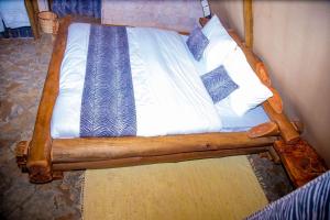 VoiBoma Simba Safari Lodge的一张带白色床单和枕头的木床