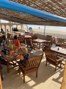 KabrousseHOTEL DU BAR DE LA MER CAP SKIRRiNG的一群坐在海滩桌子上的人