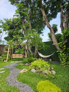 井里汶Roemah Uli Cirebon的花园设有吊床、长凳和树木