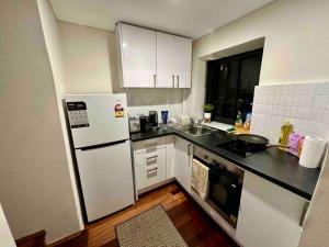 悉尼NY Special Granny Flat in Mosman的厨房配有白色橱柜和白色冰箱。