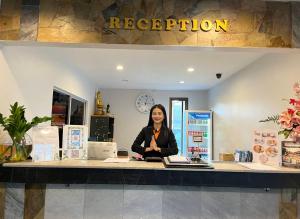 武里南Siam Boutique Hotel โรงแรมสยามบูทีค的坐在商店柜台的女人