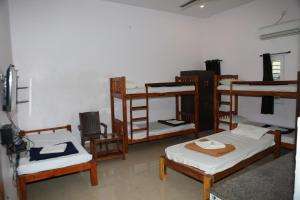 黎明之村Blissful Haven Art House - near entrance to Auroville的一间设有几张双层床和椅子的房间