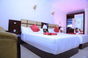 亚的斯亚贝巴Sunland International Hotel的一间卧室配有两张带红色枕头的大床