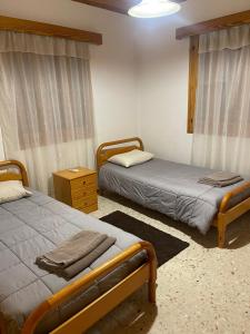 奥莫多斯Omodos Village Houses的一间卧室设有两张床和床头柜。