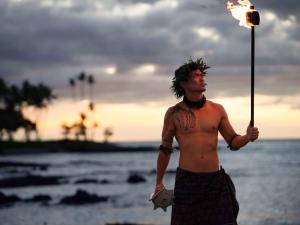 瓦克拉Fairmont Orchid的手持火 ⁇ 站在海滩上的无衬衫男子