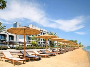 拉纳卡Mercure Larnaca Beach Resort的海滩上的一排椅子和遮阳伞