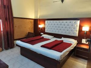 新德里王子宫殿酒店（绿色酒店）的一间卧室配有一张大床和两个红色枕头