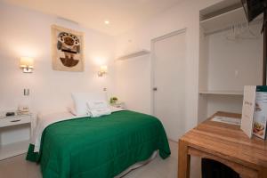 帕拉卡斯Hotel Riviera Inka Paracas的一间卧室配有一张绿色的床和一张桌子
