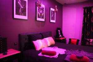 弗卢瓦拉克SECRET33的紫色客房,配有一张带粉红色床单和枕头的床