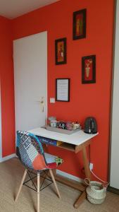 VauréalChez Laurence & RV的橙色墙壁的房间里一张桌子和一把椅子