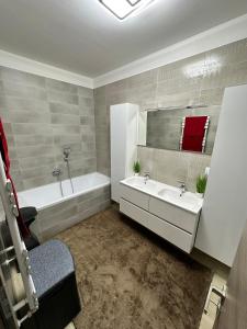 德布勒森VRG 1 Exkluzív Apartman的浴室设有2个水槽、浴缸和镜子
