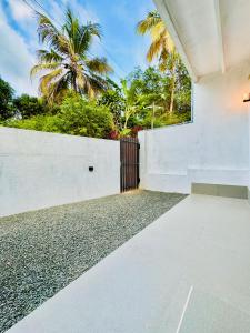 韦利格默Ru Retreat Weligama的白色的房子,有围栏和棕榈树