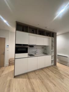 New BedfontLondon Heathrow Airport Apartment Voyager House Terminal 12345 - EV electric and Parking available的厨房铺有木地板,配有白色橱柜。