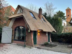 瓦瑟纳尔Cottage Guest House in Wassenaar的茅草屋顶的小砖屋