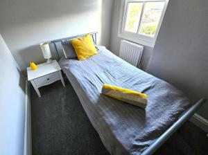 莱斯特Knighton Villa的一间卧室配有一张带黄色枕头的床和窗户