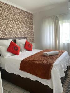 马盖特Dwengu Guest house的一间卧室配有一张带红色枕头的大床