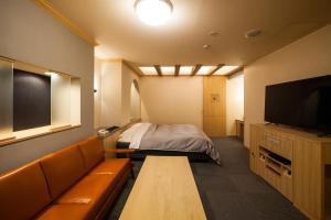 富山Hotel Torni ホテル トルニ的客房设有床、沙发和电视。