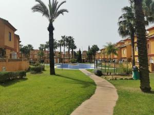莱佩Chalet Islantilla "Costa de la Luz"的一条穿过棕榈树和房屋的公园的小路