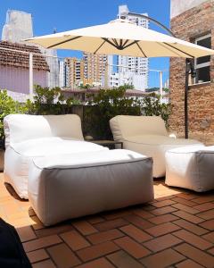 萨尔瓦多Viver Bahia Pousada的庭院里设有两张白色的沙发和一把遮阳伞