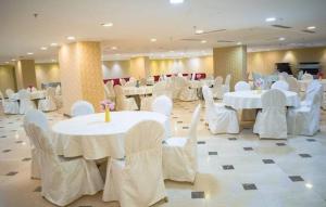 麦加فندق إي دبليو جي العزيزية的宴会厅配有白色的桌子和白色的椅子