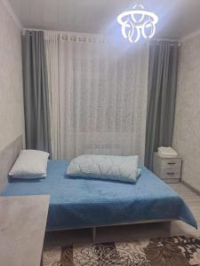 卡拉科尔GuestHouse "ERKIN"的一间卧室配有蓝色的床和吊灯。