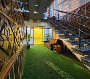 斯利那加Behtereen resort的大楼内带绿色地毯和楼梯的走廊
