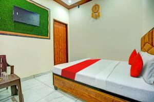 KurukshetraOYO Hotel Patiala的一间卧室配有一张带红色枕头的床和一台电视。