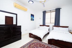 阿克拉Stay Play Away Residences - 3 bed, Airport Residential, Accra的配有电视和梳妆台的客房内的两张床