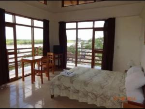 YurimaguasHostal El Puerto的卧室配有床、桌子和窗户。