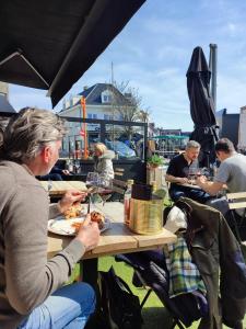 克诺克－海斯特Le Knok'Koon Un cocon à Knokke avec garage et emplacement gratuits的一群坐在餐桌上吃食物的人