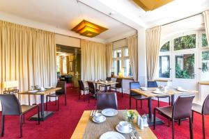 罗拉赫Hotel Villa Elben Lörrach bei Basel的餐厅设有桌椅和窗户。