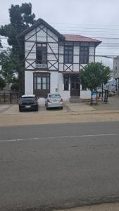 帕普多Hostal La Casona的两辆汽车停在大楼前
