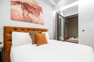 海若克利欧Royal Gold City Suites by Estia的卧室配有一张白色大床,墙上挂有绘画作品